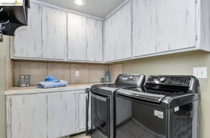 Laundry room featuring cabinet space, separate washer and dryer, and light tile patterned floors