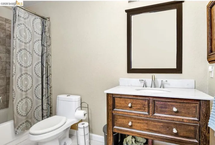Bathroom with vanity, a textured wall, and shower / bathtub combination with curtain