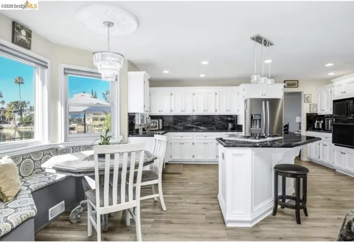 Kitchen with black appliances, a kitchen breakfast bar, breakfast area, white cabinetry, and a center island