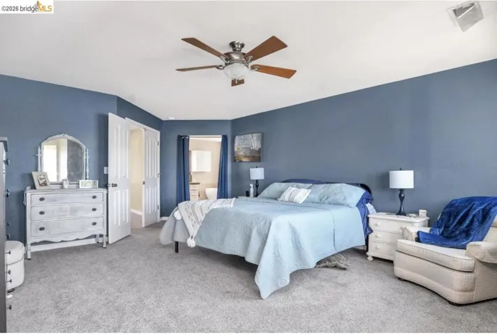 Carpeted bedroom with a ceiling fan and ensuite bath
