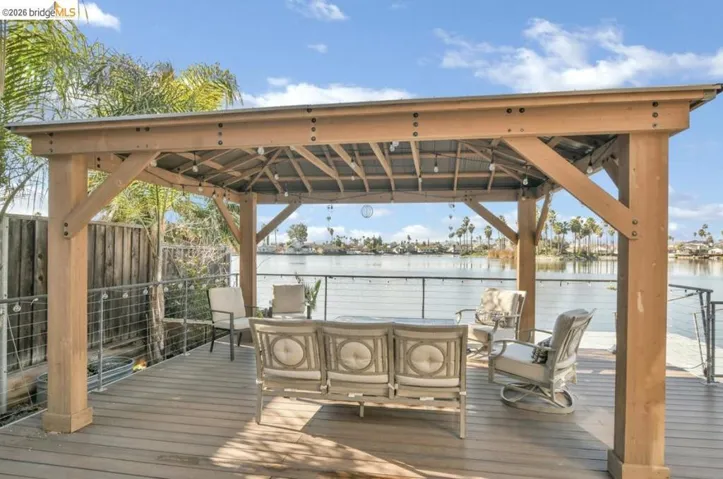 Wooden deck featuring outdoor seating, a water view, and a gazebo