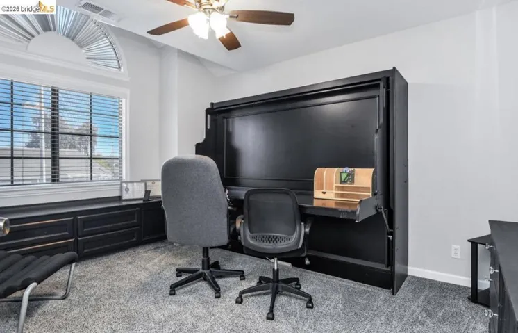 Home office featuring light carpet and a ceiling fan