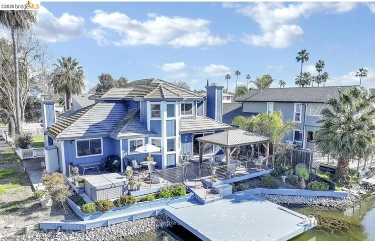 Rear view of property with a gazebo, a chimney, a patio, a tile roof, and a water view