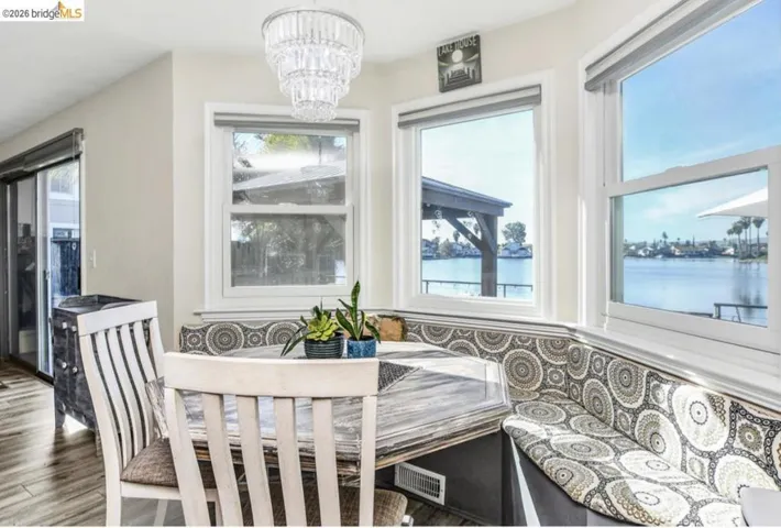 Dining room with breakfast area, suspended lighting, a water view, and wood finished floors