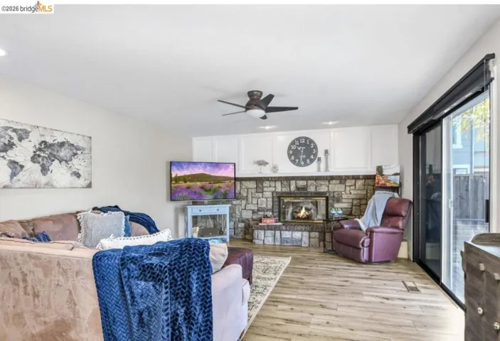 Living room with wood finished floors, a fireplace, a ceiling fan, and recessed lighting