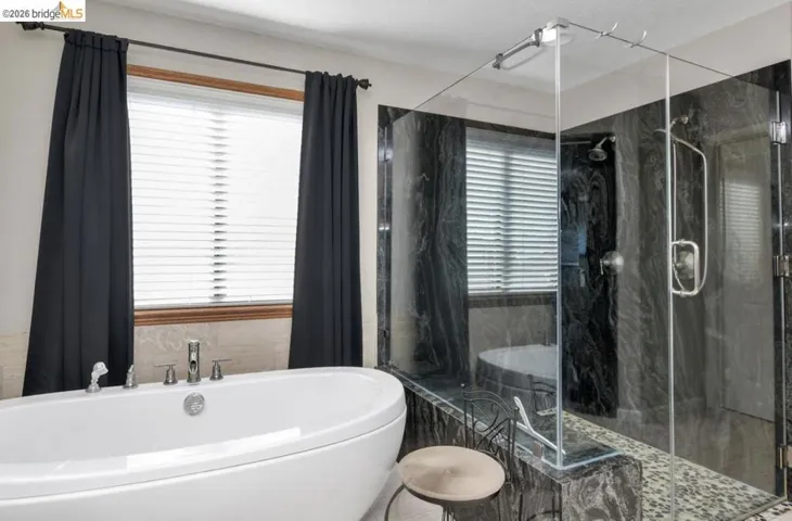 Full bath featuring a freestanding bath and a marble finish shower