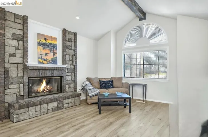 Sitting room with a fireplace, wood finished floors, and beamed ceiling