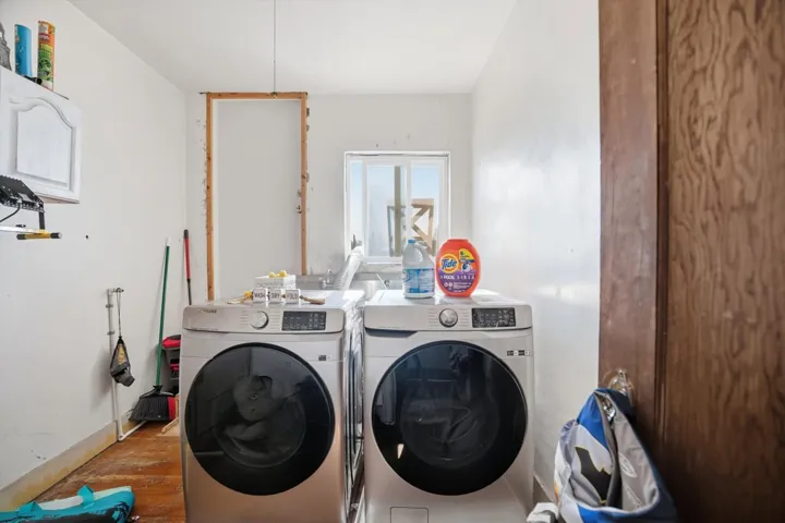 Laundry area featuring wood finished floors and washing machine and clothes dryer