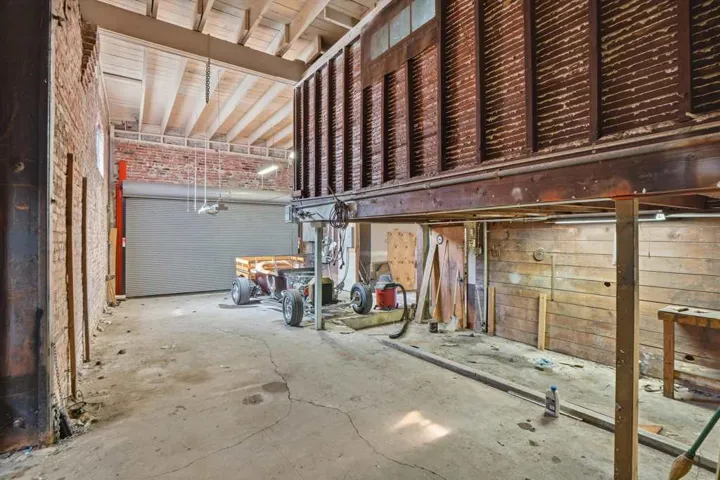 Miscellaneous room featuring brick wall and unfinished concrete floors