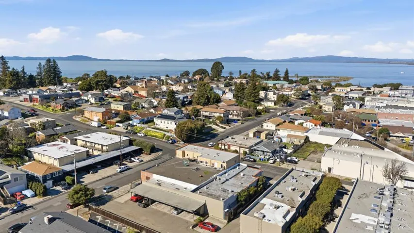 Aerial view of property and surrounding area with a water and mountain view and nearby suburban area