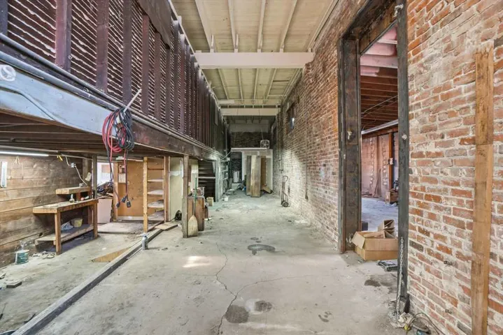 Misc room with brick wall and unfinished concrete flooring