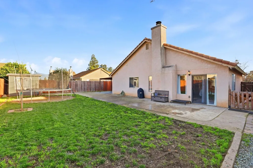 Back of house featuring a patio area, a trampoline, stucco siding, and a fenced backyard