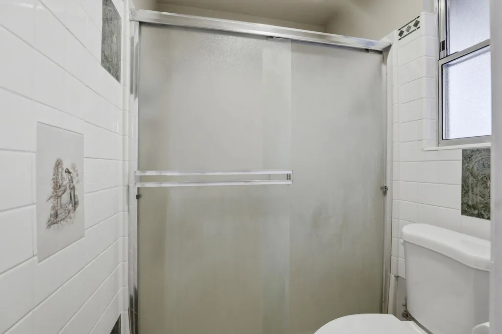 Full bathroom featuring a shower stall and tile walls