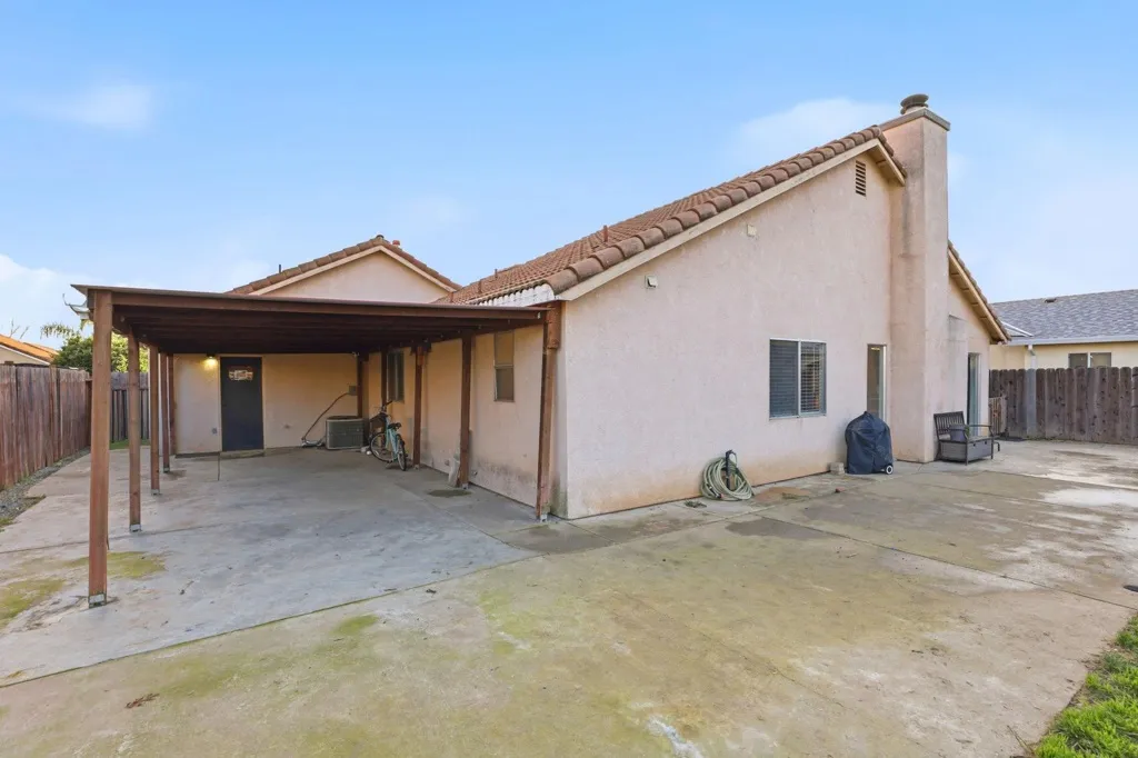 Back of house featuring a fenced backyard, stucco siding, a chimney, and a patio area