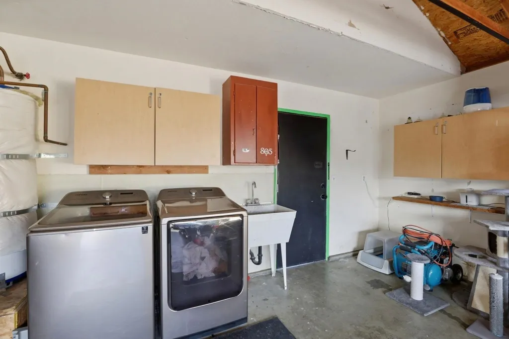 Laundry room with unfinished concrete flooring, water heater, independent washer and dryer, and cabinet space