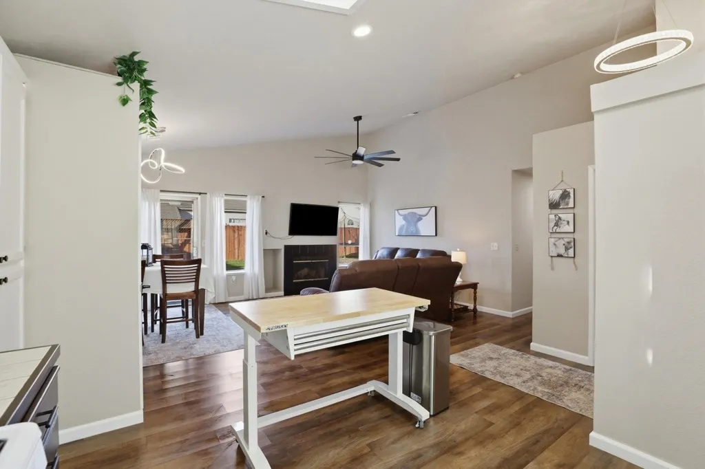 Living room featuring lofted ceiling, dark wood-type flooring, recessed lighting, ceiling fan, and a glass covered fireplace