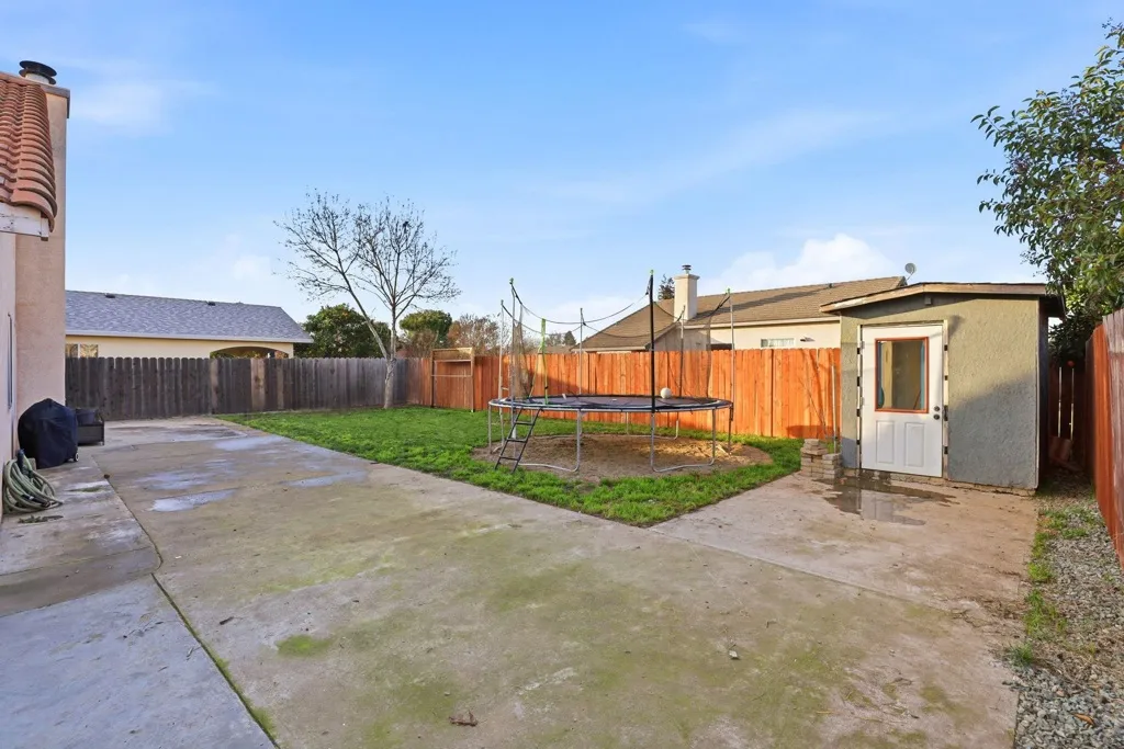 Fenced backyard featuring a storage shed, a patio area, and a trampoline