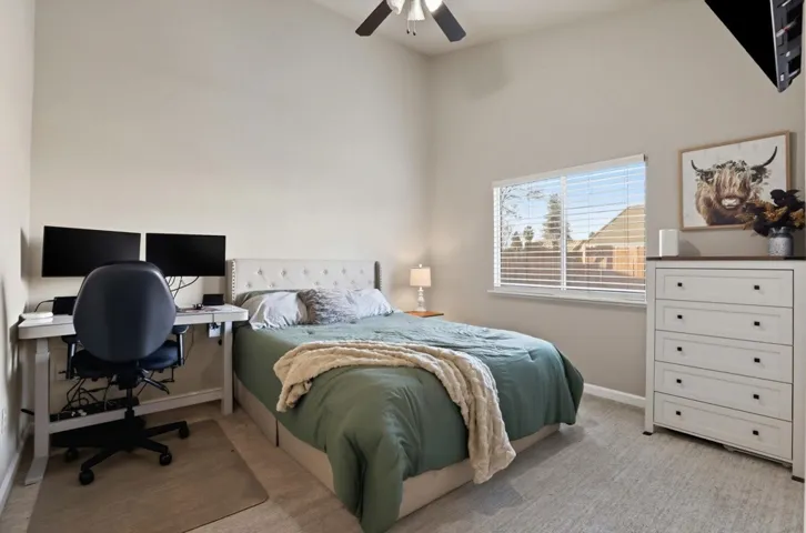 Bedroom with a desk, light colored carpet, and ceiling fan