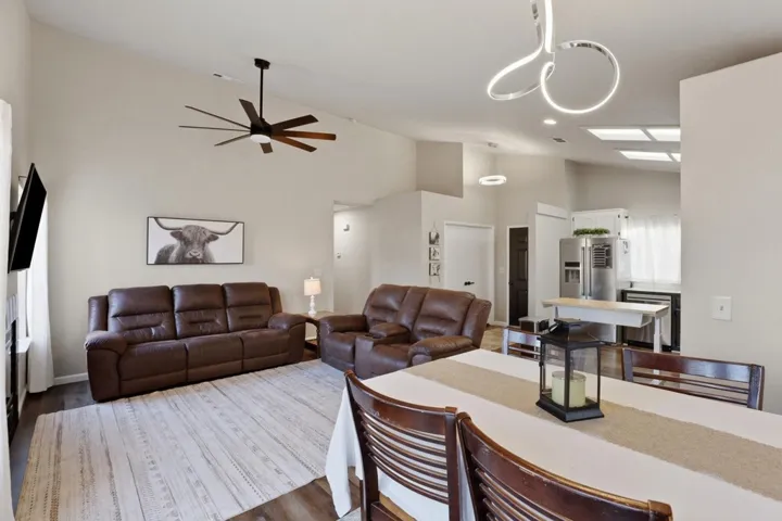 Living room featuring vaulted ceiling, wood finished floors, and ceiling fan