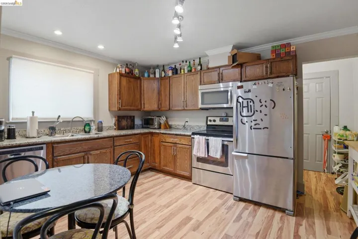 Kitchen featuring stainless steel appliances, light wood-style floors, wood finish cabinetry, and ornamental molding