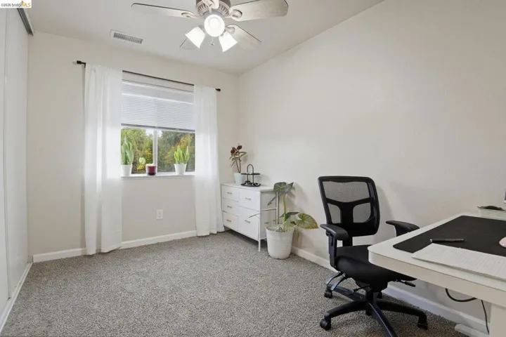 Home office with light carpet and ceiling fan