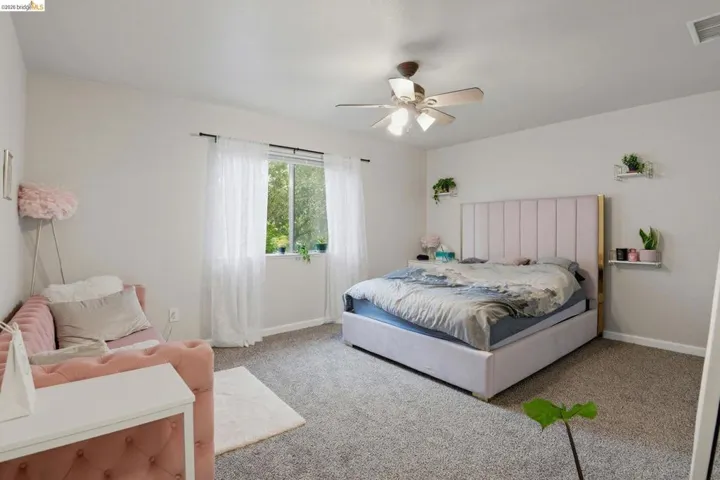Carpeted bedroom with ceiling fan and baseboards