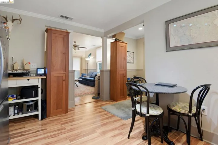 Dining room featuring ornamental molding, light wood finished floors, ornate columns, and ceiling fan