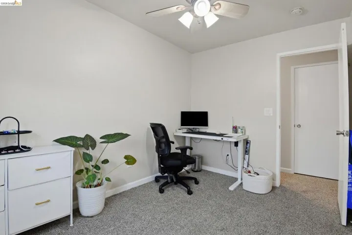 Home office with light carpet and ceiling fan