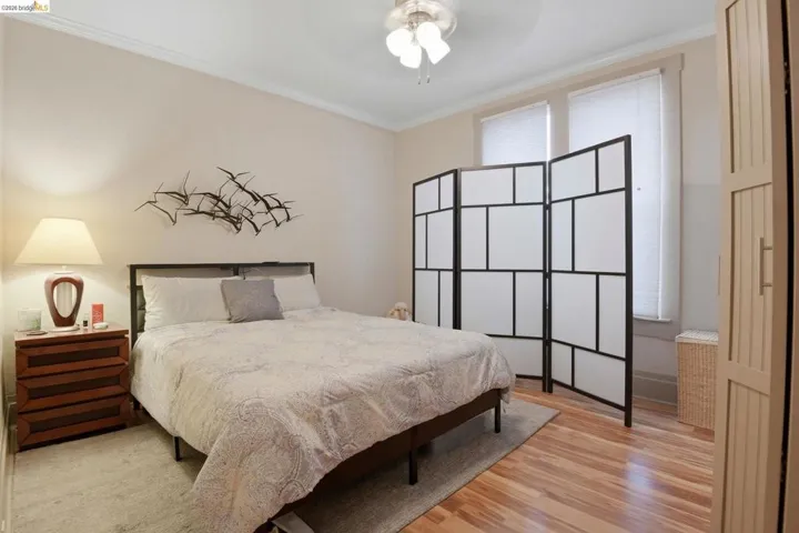 Bedroom featuring ornamental molding, light wood-style flooring, and a ceiling fan