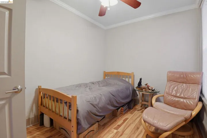 Bedroom featuring wood finished floors, ornamental molding, and a ceiling fan