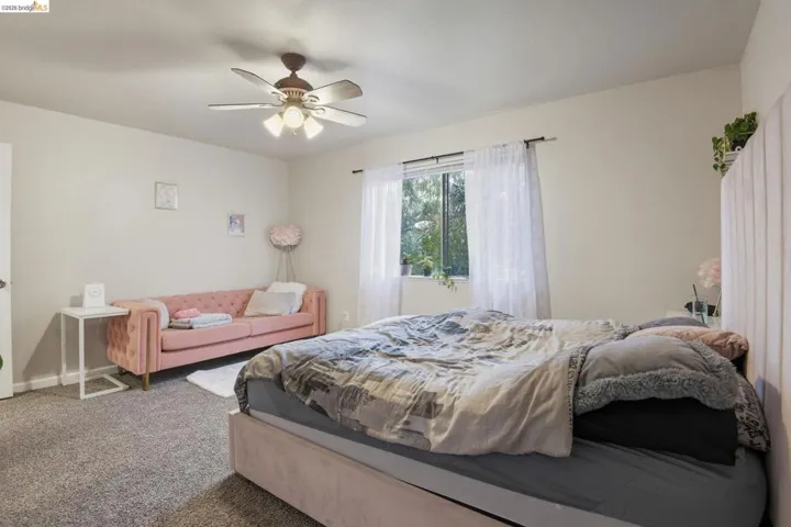 Carpeted bedroom featuring a ceiling fan and baseboards