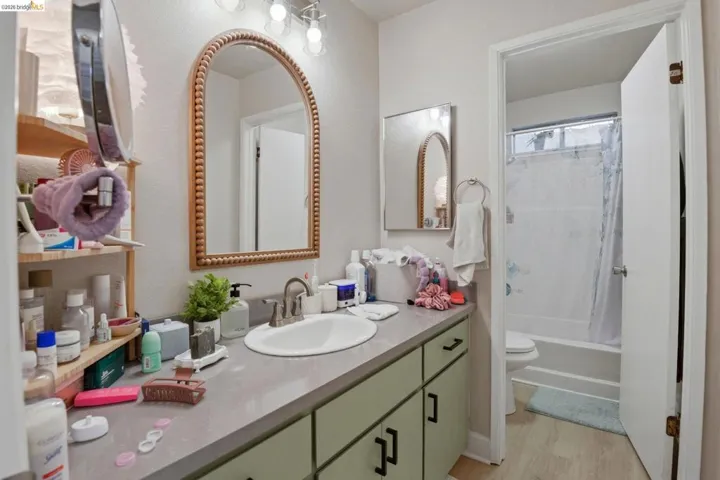 Full bath with vanity, shower / tub combo, and light wood-style floors