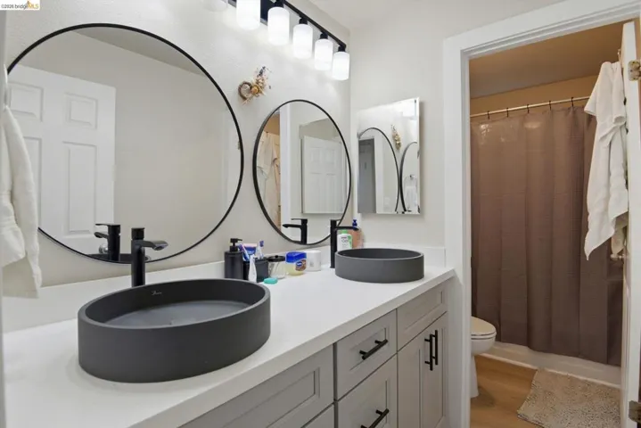 Full bathroom featuring double vanity and light wood finished floors