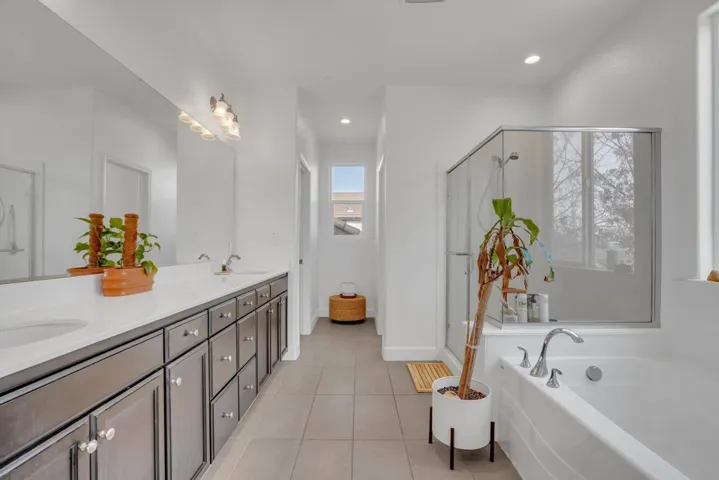 Bathroom featuring double vanity, a stall shower, a garden tub, light tile patterned floors, and recessed lighting