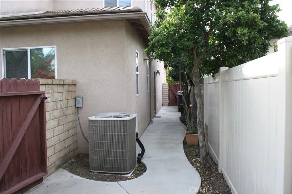 Double-Gated Utility Aisle on the side of the house with Pool Equipment and A/C and a door into the garage.