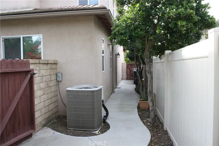 Double-Gated Utility Aisle on the side of the house with Pool Equipment and A/C and a Door into the Garage.