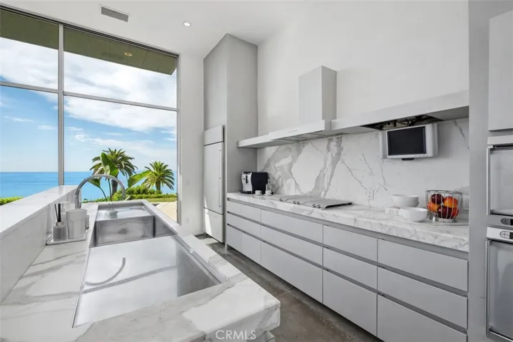 Kitchen is very sleek with marble counters and stainless steel sink. Many drawers for storage.