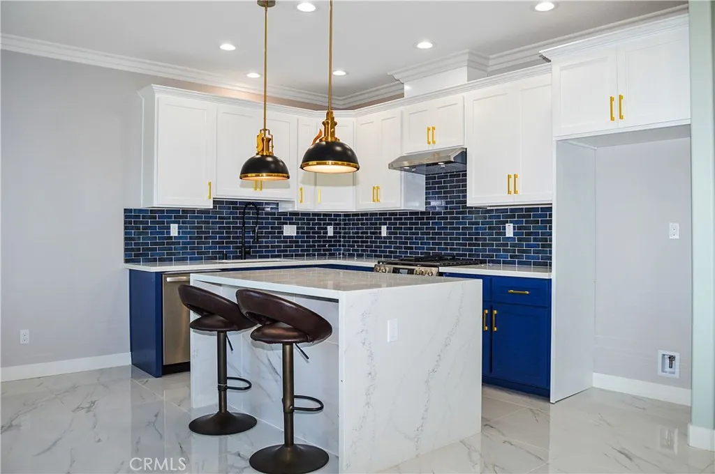 Unit 2 - Well-appointed kitchen with range, hood, dishwasher, quartz counters, waterfall edge on island, and custom lighting