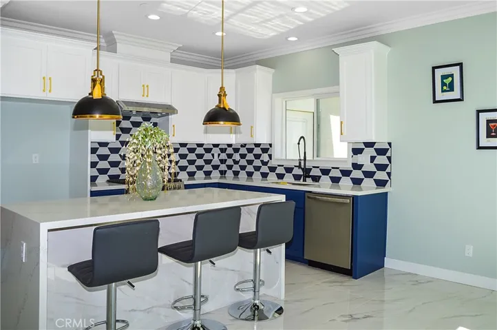 Unit 1 - Designer-perfect kitchen with range, hood, dishwasher, tile backsplash, quartz counters, waterfall edge on island, and custom lighting