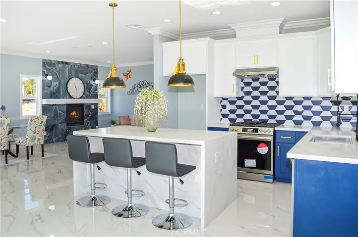Unit 1 - Designer-perfect kitchen with range, hood, dishwasher, tile backsplash, quartz counters, waterfall edge on island, and custom lighting