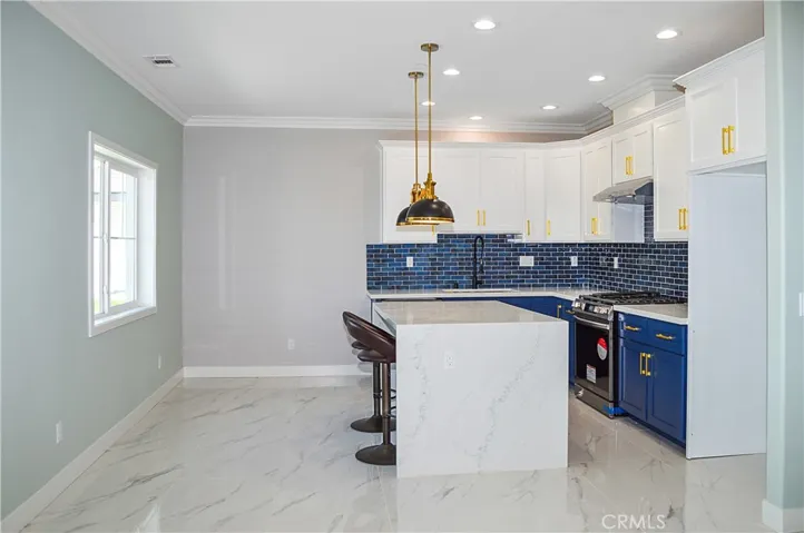 Unit 2 - Well-appointed kitchen with range, hood, dishwasher, quartz counters, waterfall edge on island, and custom lighting