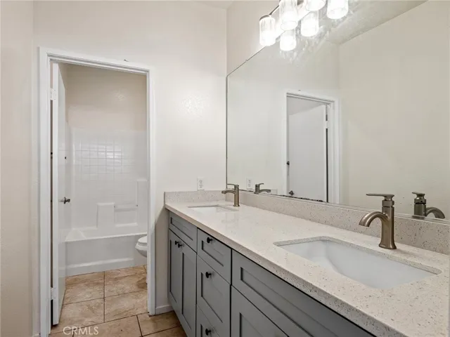 Enjoy the updated hallway full bathroom showcasing a new dual-sink vanity with ample storage, tile flooring and upgraded lighting that creates a bright and welcoming space.