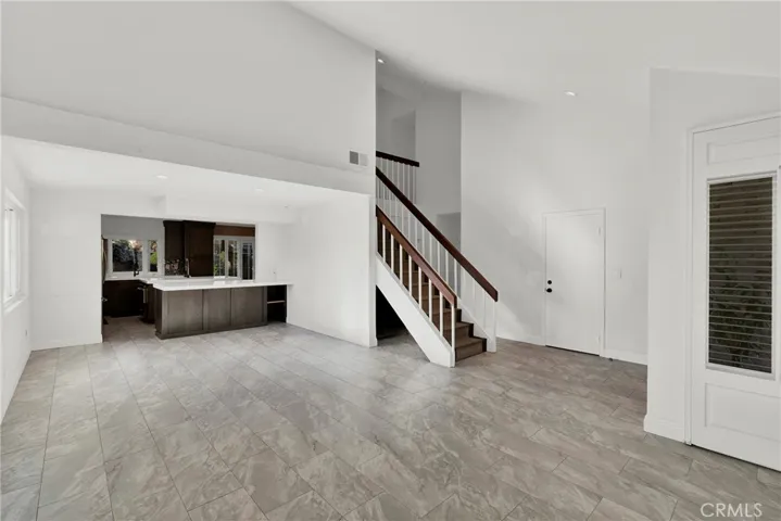 Entry to living room and view into kitchen. Door at bottom of stairs is access to the garage