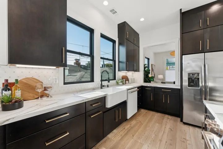 Kitchen featuring stainless steel fridge with ice dispenser, light wood-style floors, backsplash, light stone counters, and dishwasher
