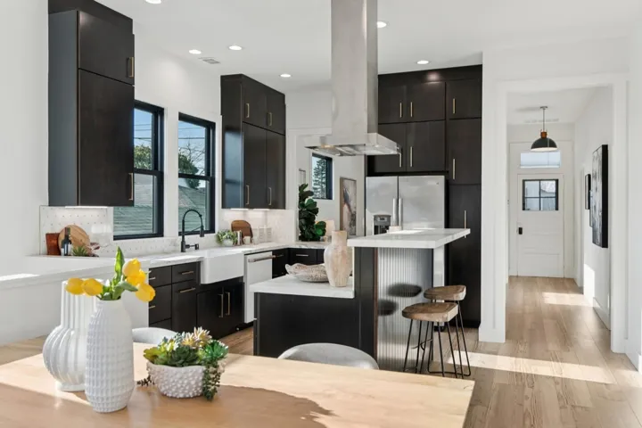 Kitchen featuring dark cabinets, a breakfast bar area, a center island, light wood-style floors, and island range hood