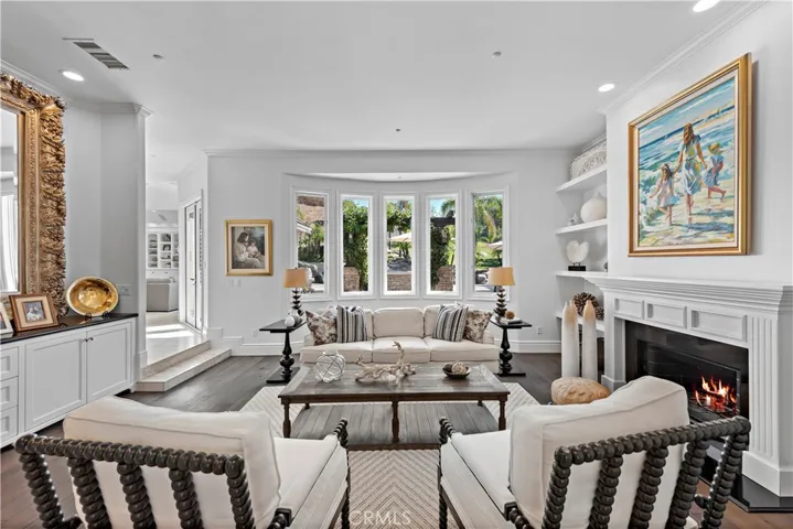 The exquisite sitting room with fireplace has a great formal built-in cabinet, amazing view of the yard, hand finished very high end wood flooring and is a quiet pleasure to relax in!