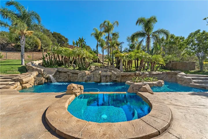 A stunning resort-caliber pool & spa offering the ultimate escape and fun featuring stonework, waterfalls, an amazing slide and mature palms and landscape evoking the ambiance of a five-start retreat!