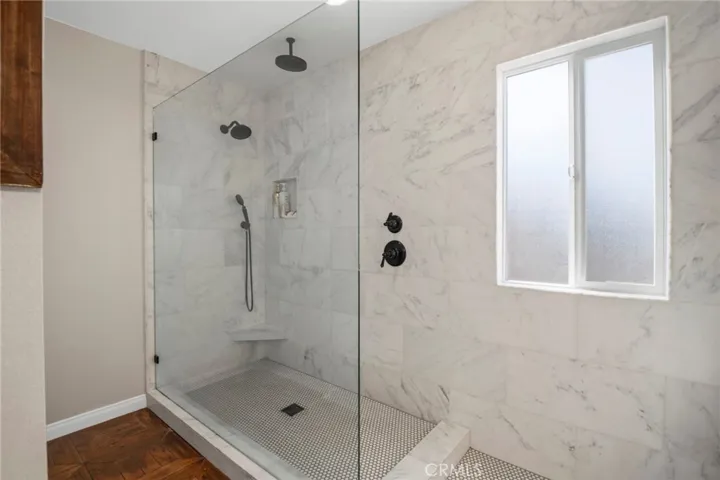Spacious walk in shower with multiple shower heads in primary bathroom.