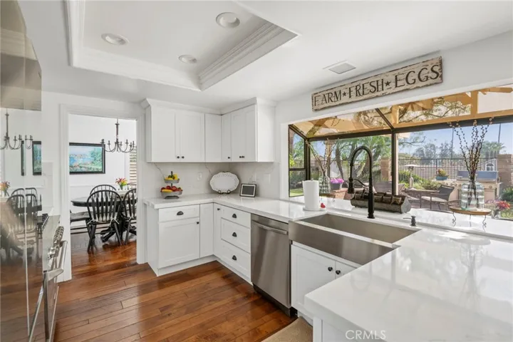 Spacious remodeled kitchen with direct view of rear yard, quartz counters, shaker cabinets, farm style sink, stainless steel appliances, & recessed lighting.