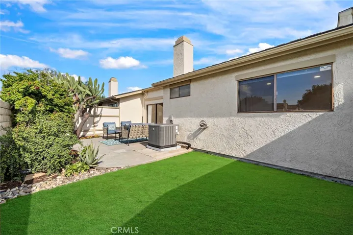 Backyard patio has artificial turf and concrete patio, plus block walls